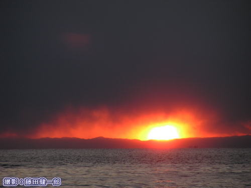 雪雲と三浦半島の間に沈む夕日